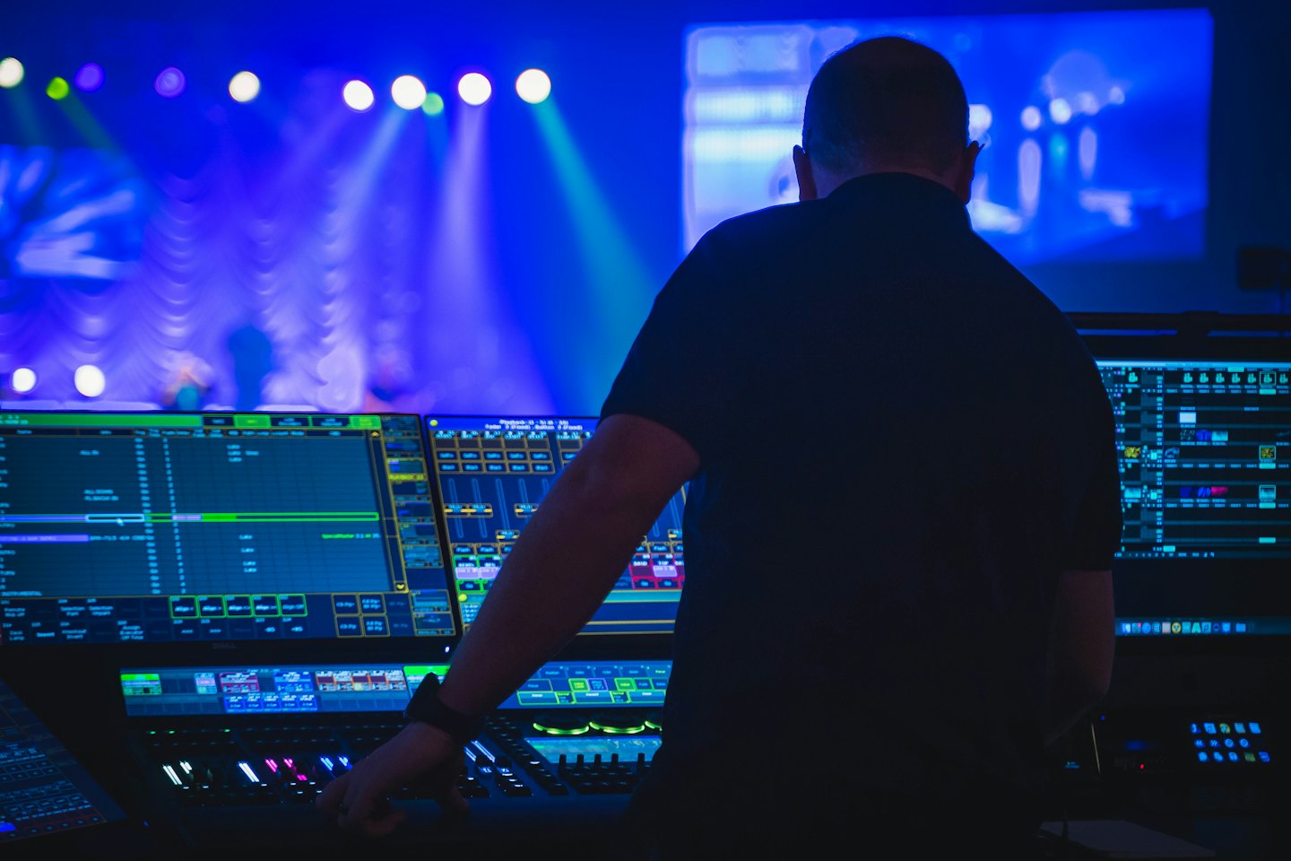 Tecnico che opera una console di controllo con più monitor.