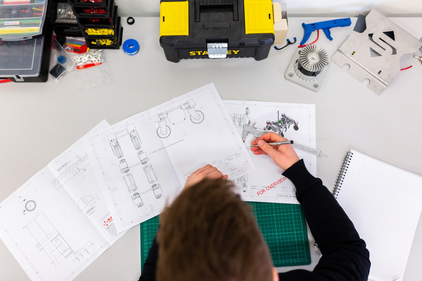 Ingegnere esamina schemi con calibro su una scrivania disordinata.